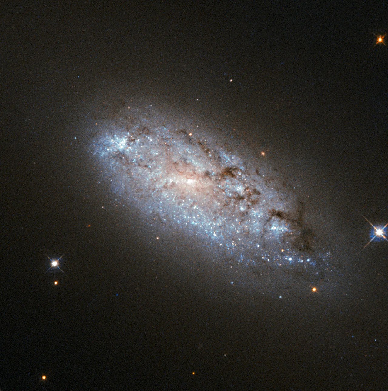 A swirl of bright stars and dust on a black background with a few bright stars