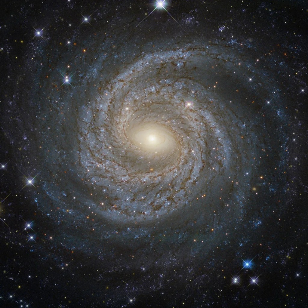 Spiral galaxy ngc 6814 with luminous arms, a glowing core, and dark dust streaking throughout the arms