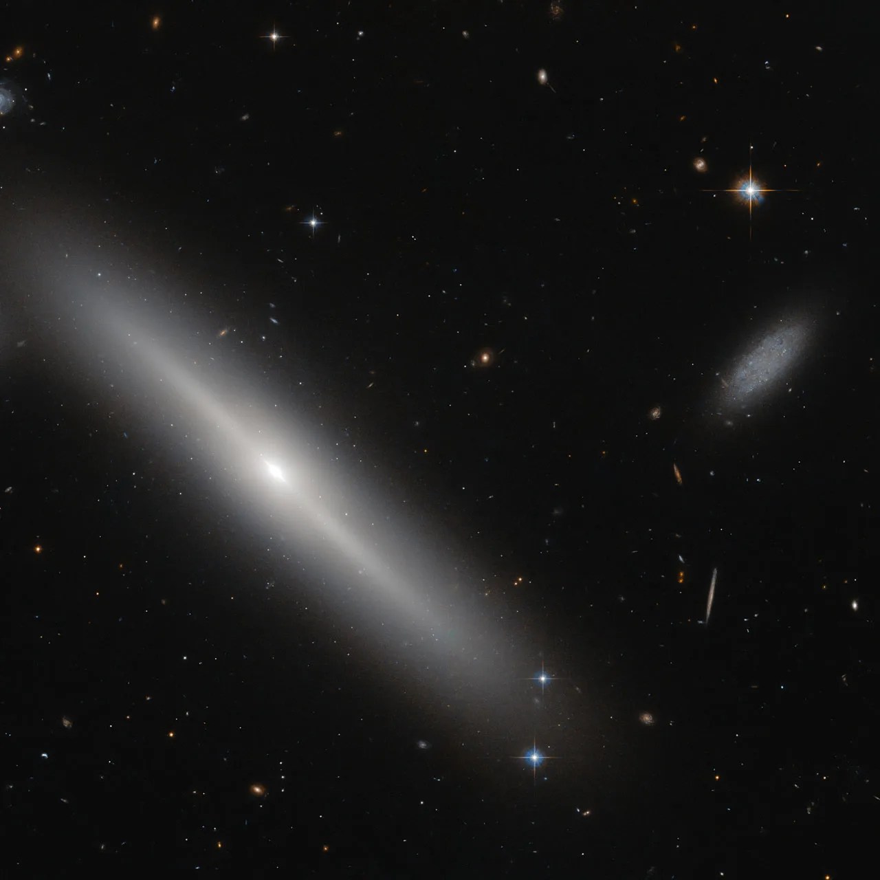 Big, bright disk galaxy next to small irregular galaxy