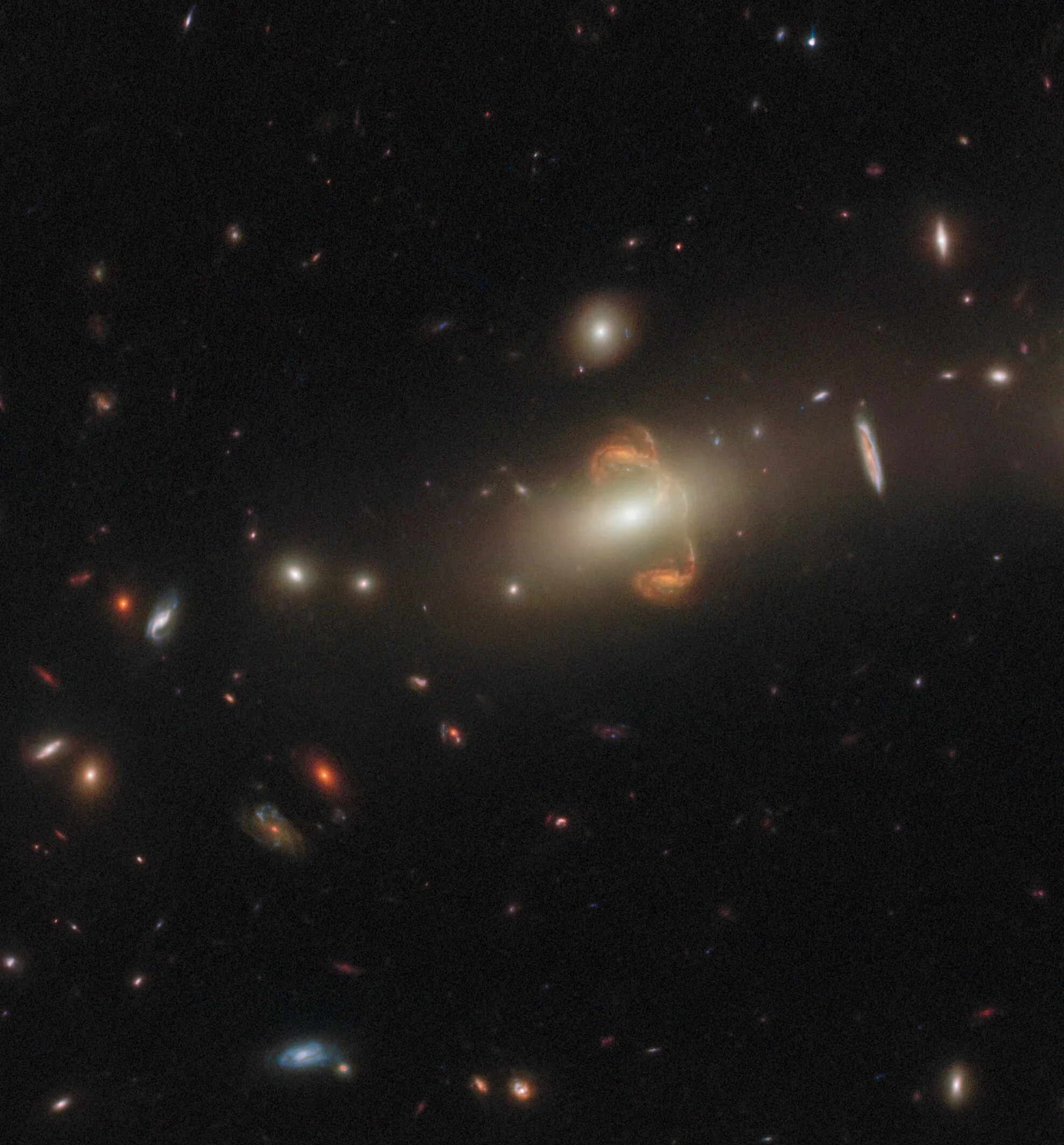 Galaxies fill the scene. large, bright-white galaxy in the center-right of the image. two reddish-gold spiral (mirrored galaxy) above and below the central galaxy on its right side.