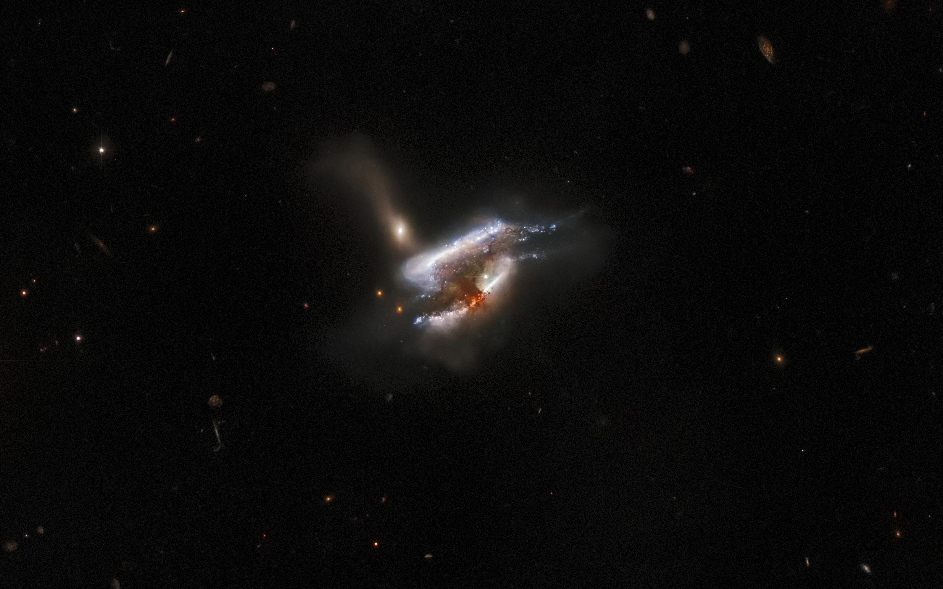 Three galaxies at center. two seen nearly edge on and angled from lower left to upper right, stacked one above the other. third galaxy perpendicular to the other two