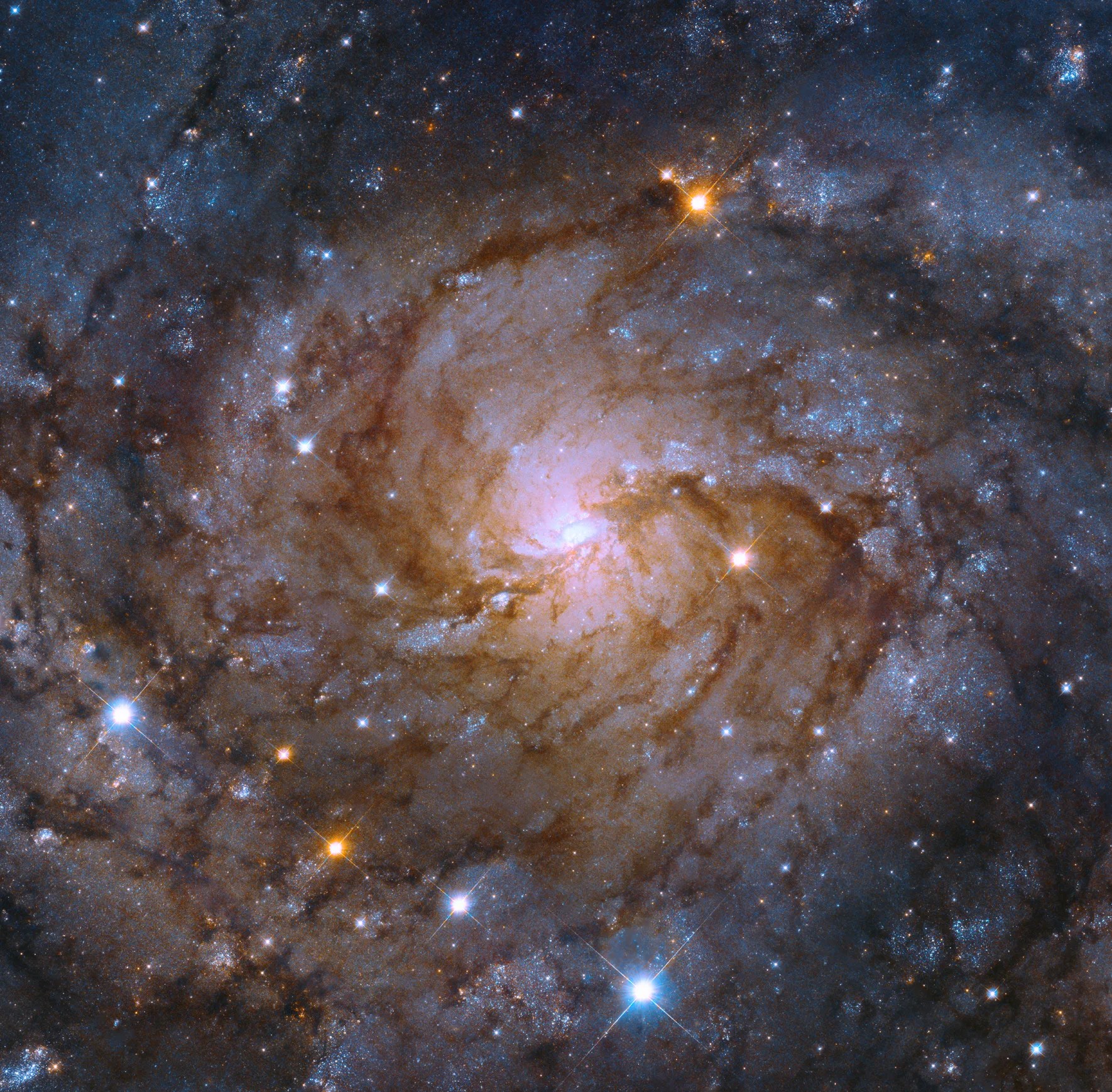 Pink, white spiral galaxy with dotted with red and blue stars, and a bright-white core, and reddish-brown dust lanes