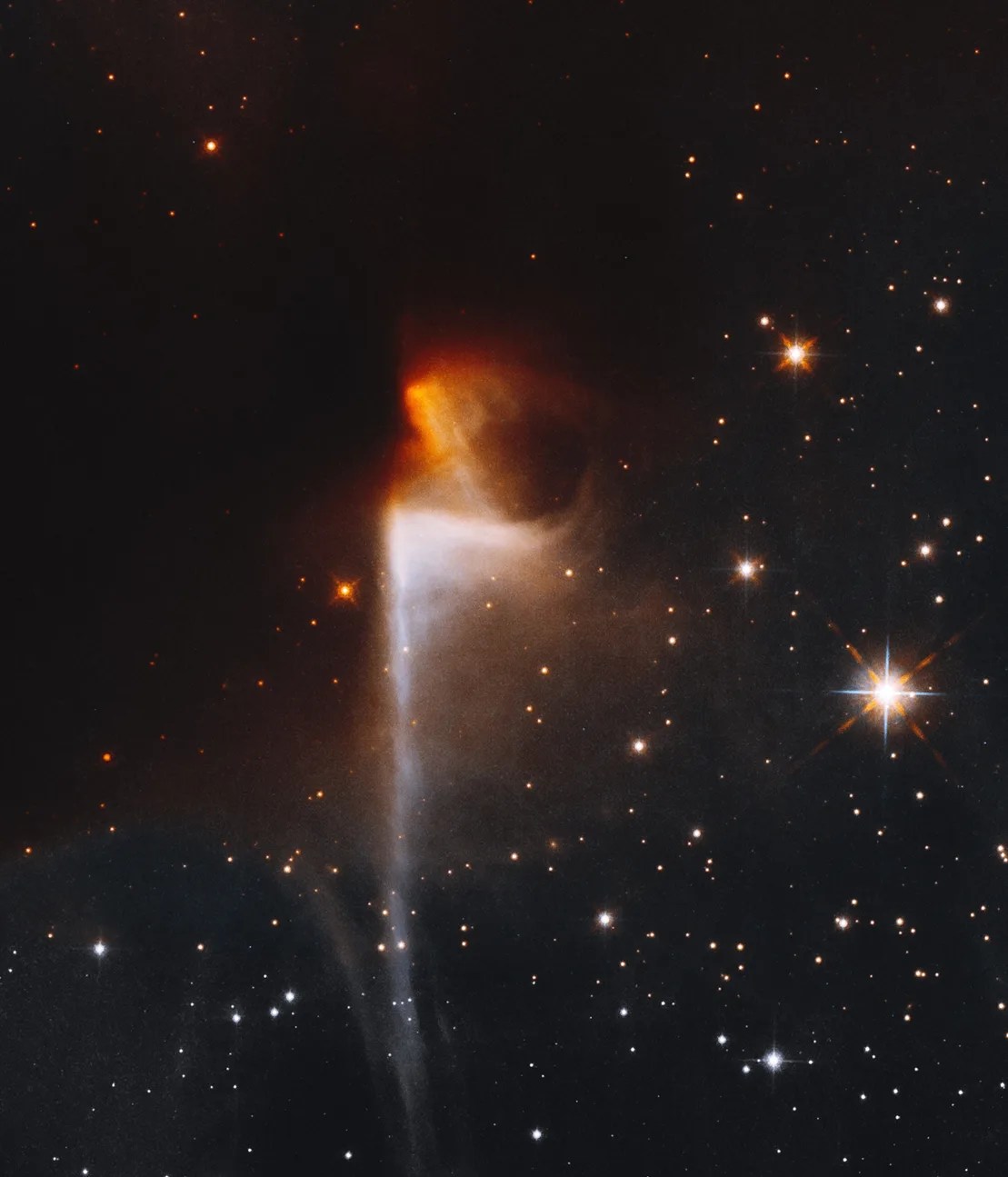 Left center: inky-black dark nebula; center: orange nebula emerges from dark nebula, with white nebula below stretching to the bottom of the image. .