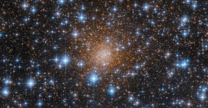 Bright, reddish-gold spherical swarm of stars fills the center of the image. Even brighter blue-white foreground stars dot the entire scene.