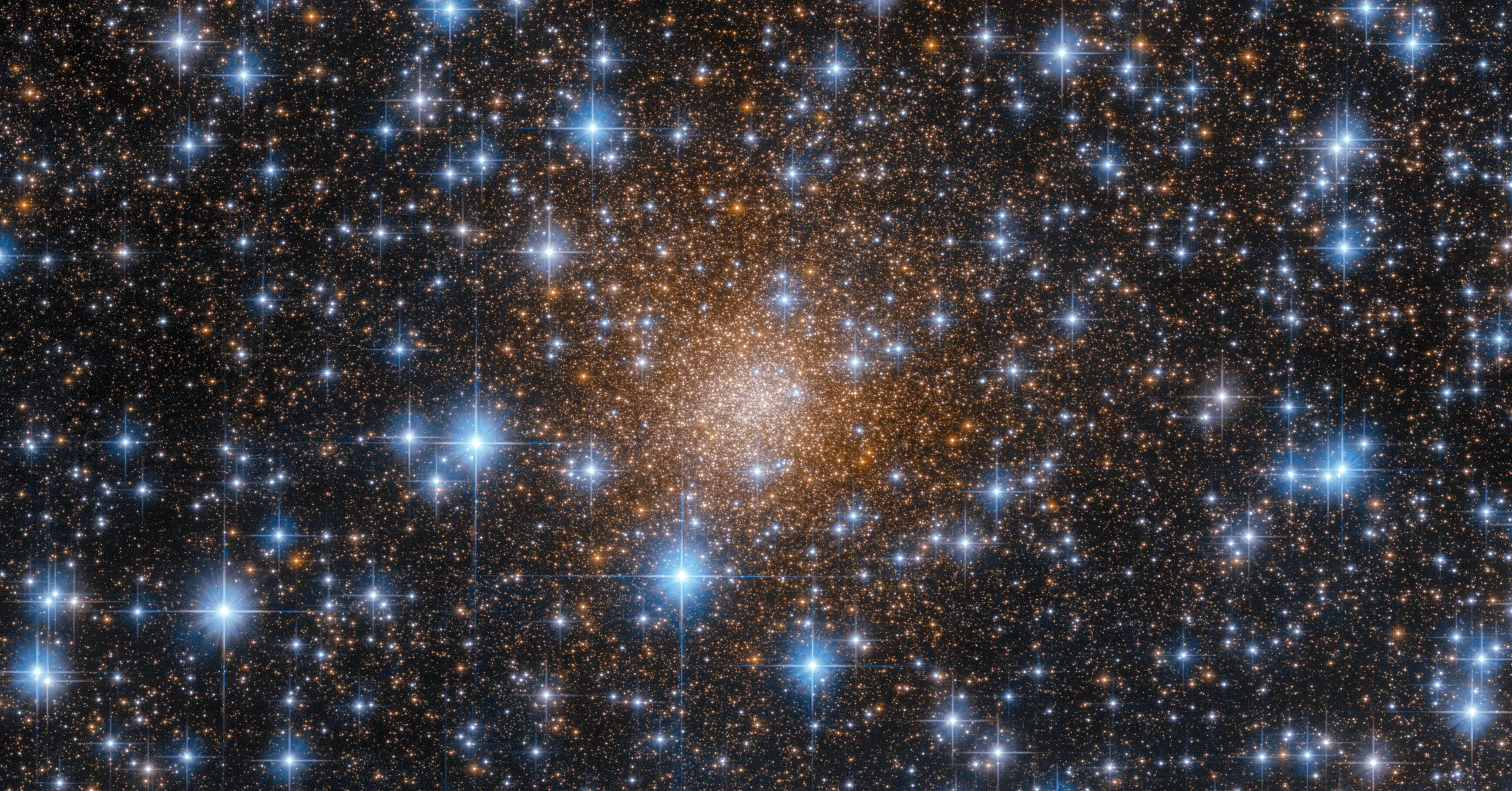 Bright, reddish-gold spherical swarm of stars fills the center of the image. Even brighter blue-white foreground stars dot the entire scene.