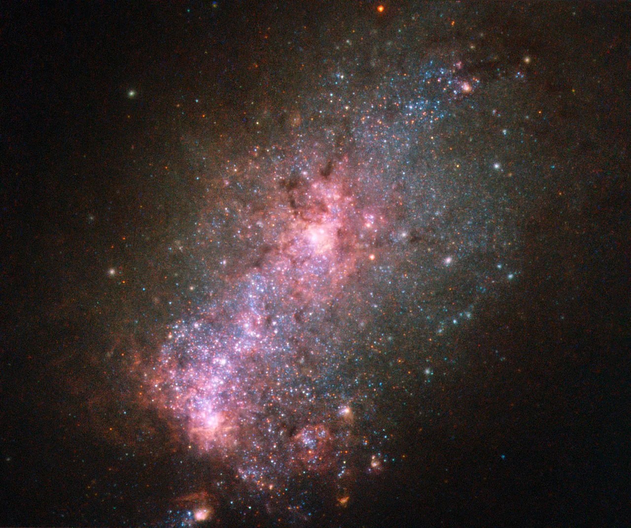 This galactic core has two bright reddish-pink concentrations of stars and gas, with pink and blue stars between them.
