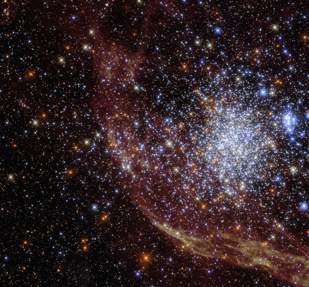 center left spherical gathering of blue-white and orange stars, reddish gas cloud extends from bottom right corner to top center