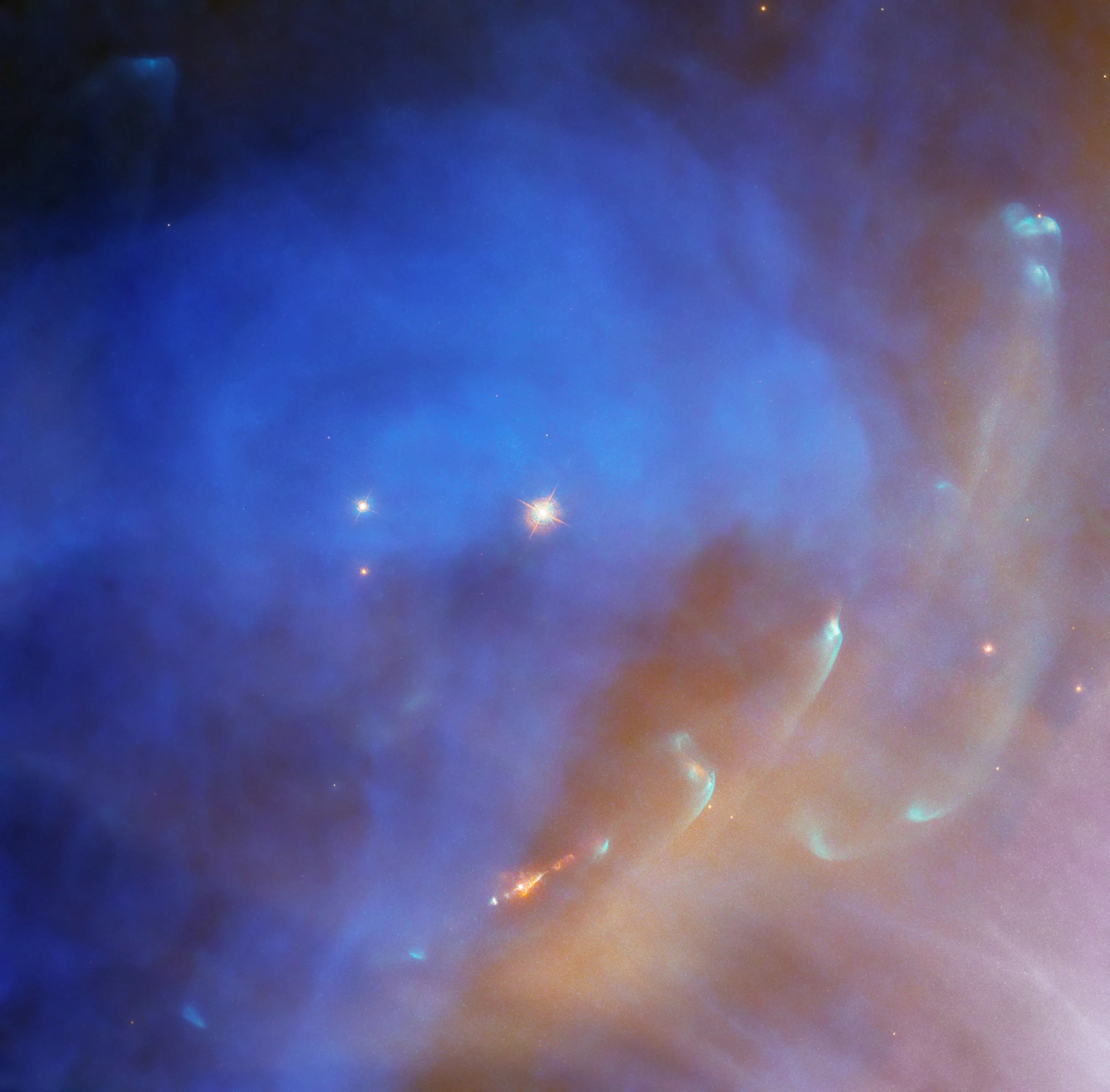 Hubble image of NGC 1977. Bright blue cloud with a reddish-orange jet (bottom, center). Far-right side and bottom right corner, reddish-orange cloud