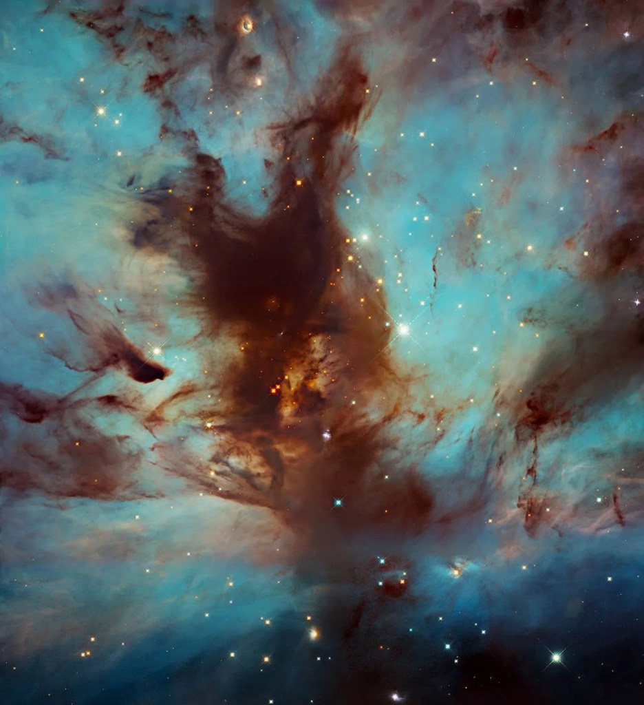 Image of a colorful blues and dark browns nebula with stars.