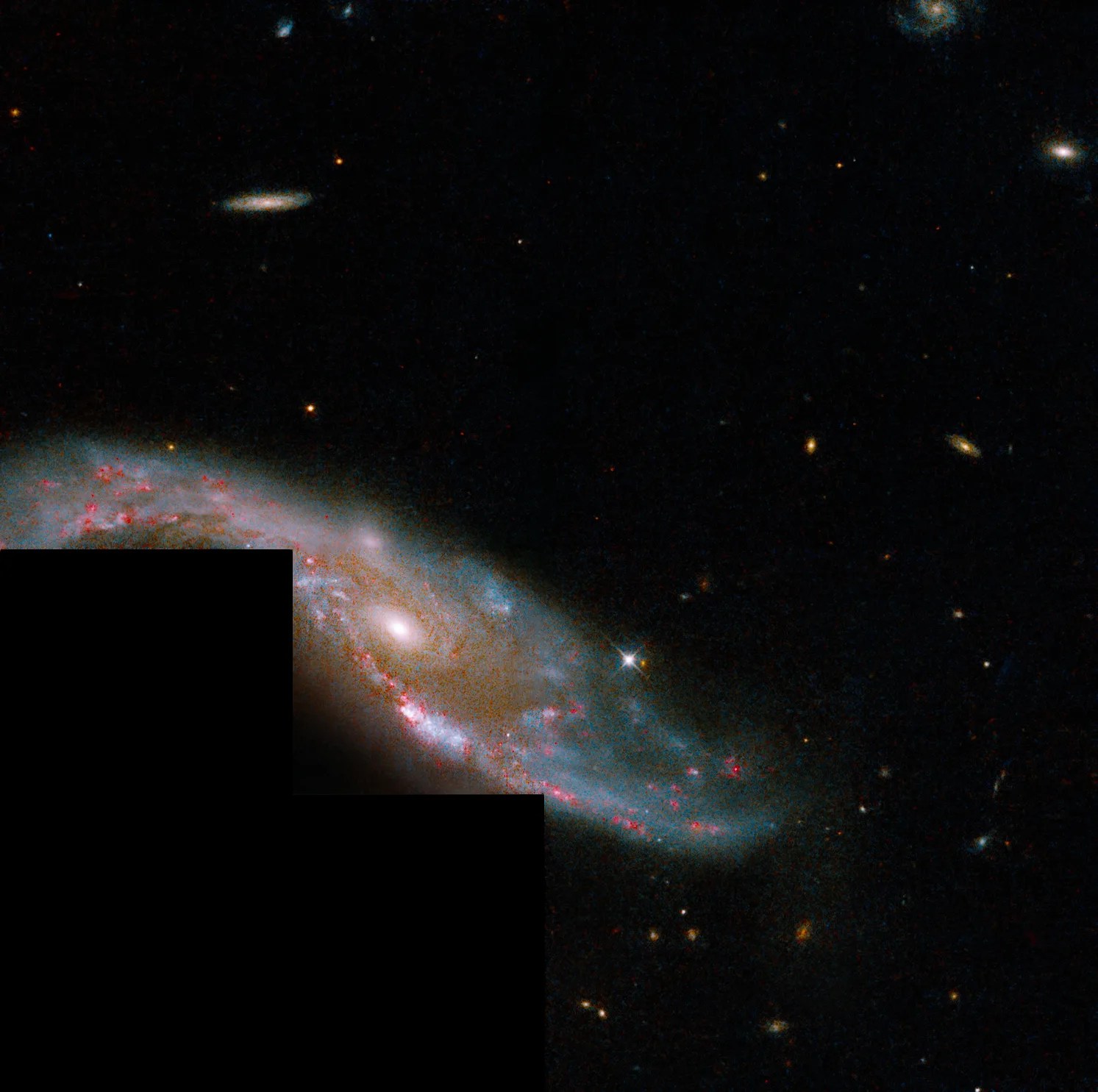 Spiral galaxy bisects the image from center left to bottom right. the lower left corner of the image is blacked out, a wfpc2 artifact.