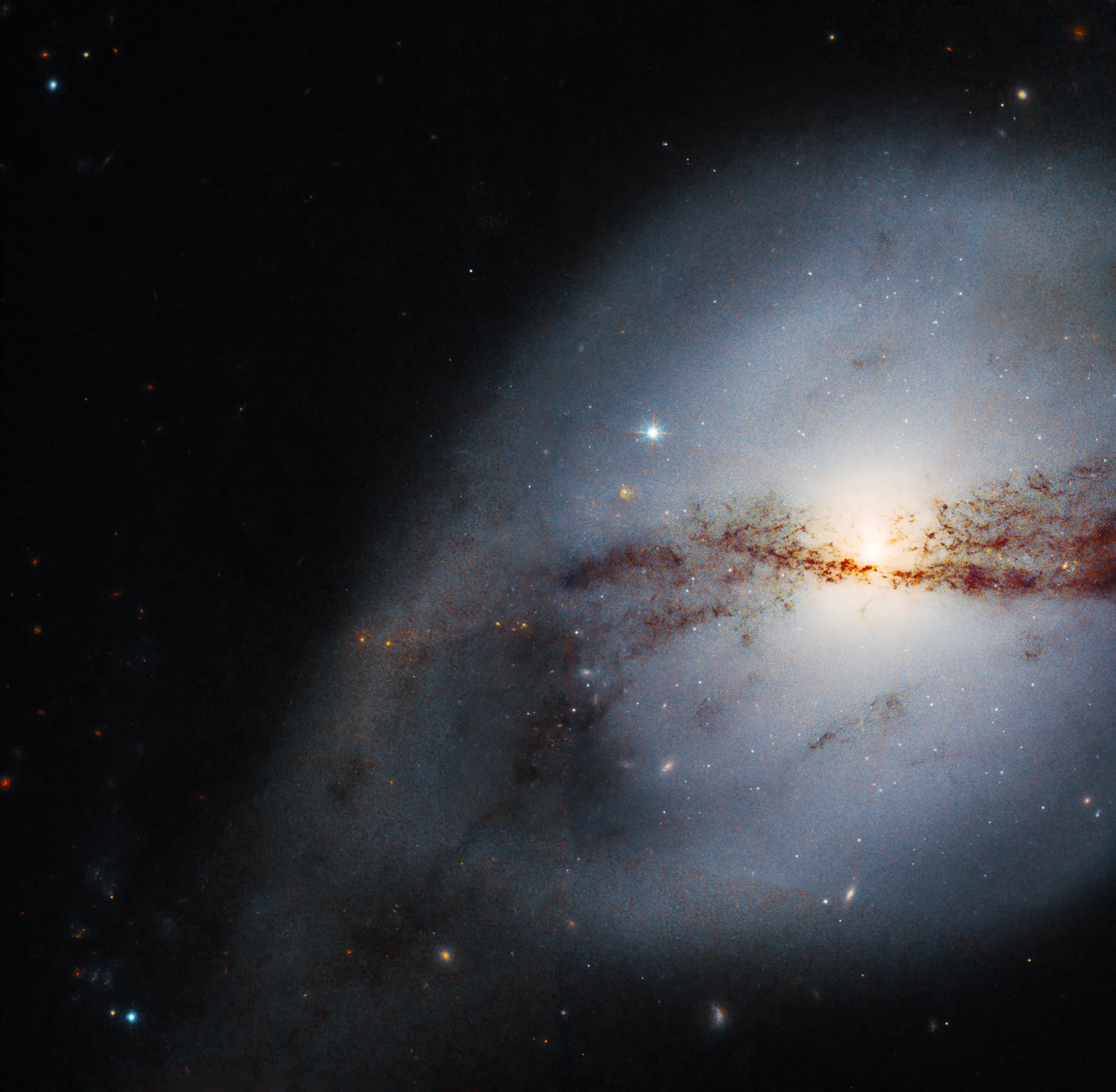 Right two-thirds of the image: nearly spherical galaxy with bright core (center right), horizontal dust lane bisects the galaxy, gas and dust loop extends to lower left of the galaxy
