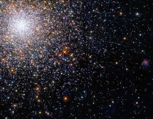 Bright-white spherical cluster of stars in the upper left corner. Stars taper off down and out to the right of the cluster against a black background. Reddish-orange stars dot the scene.