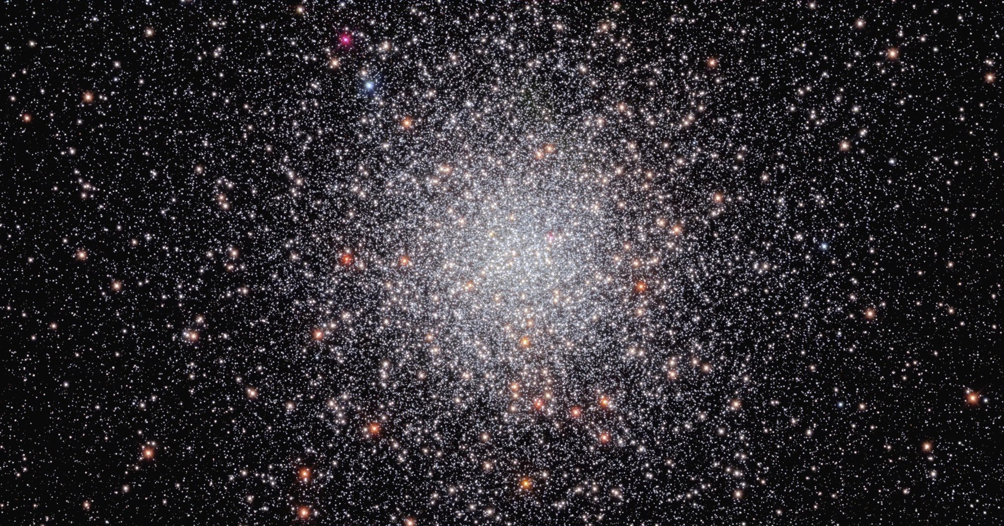 Center of the image is filled with a sphere of white stars. a smattering of orang-white stars dots the sphere. they are set against a black background that holds a smattering of stars.