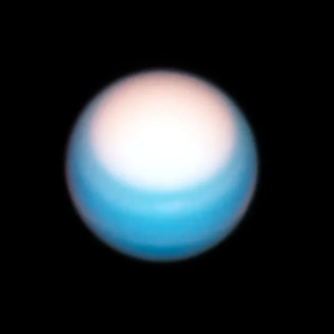 Hubble 2021 image of Uranus. Bright white circle comprises the top third of the planet. Most of the planet is a bright blue color.