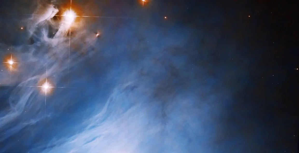Bright blue cloud fills the scene, orange-red rings surround bright-white stars in the upper-left corner of the image