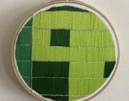 Photo of embroidered art, a green image representing a Landsat satellite image of earth