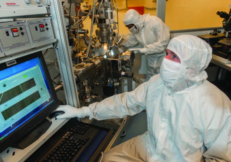 Photo of scientist in lab gear working on computer testing chips