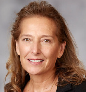Portrait photo of a smiling woman with long dark blonde hair and wearing a dark blazer