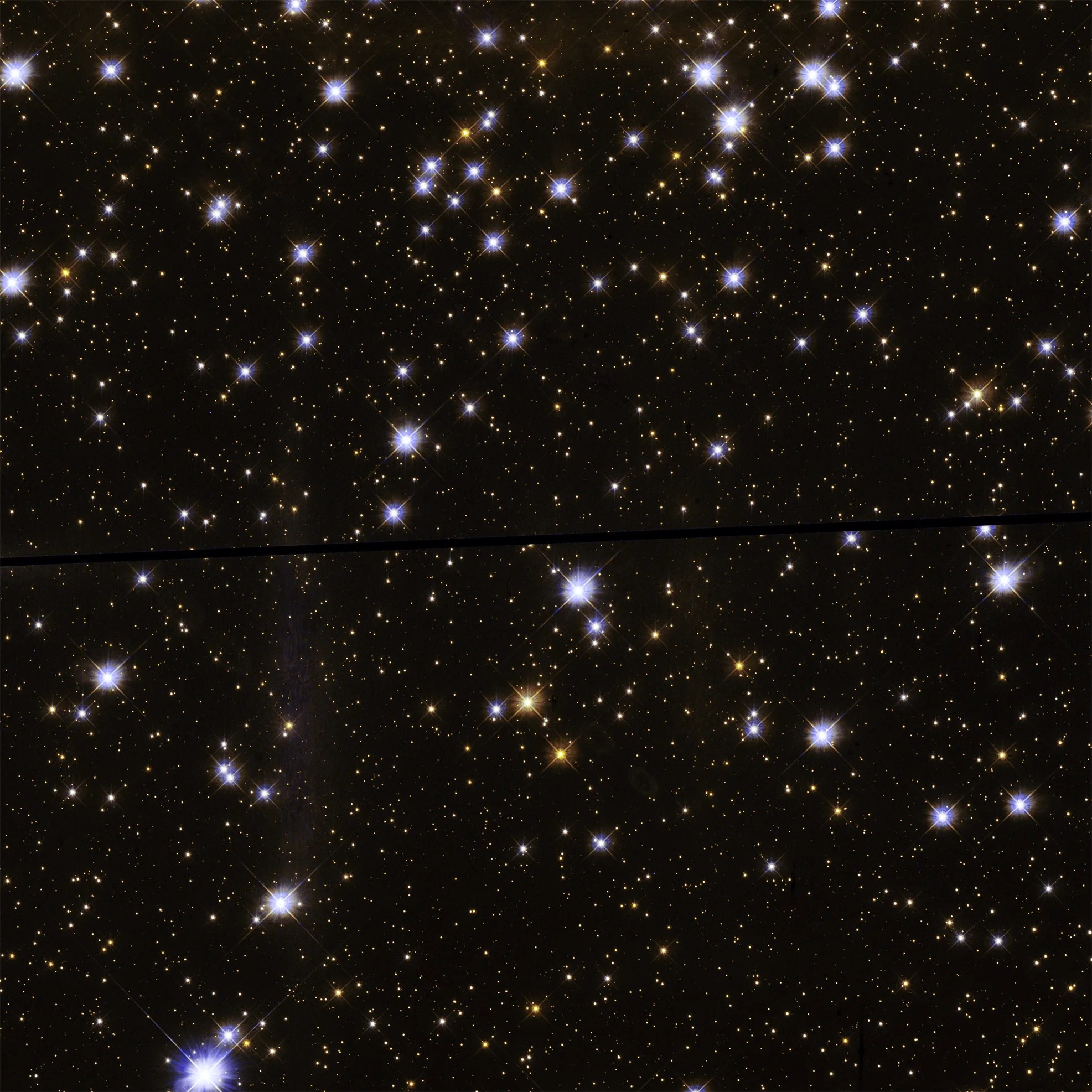 An open cluster of stars, with many small stars in the background and several larger white and yellow in the foreground.