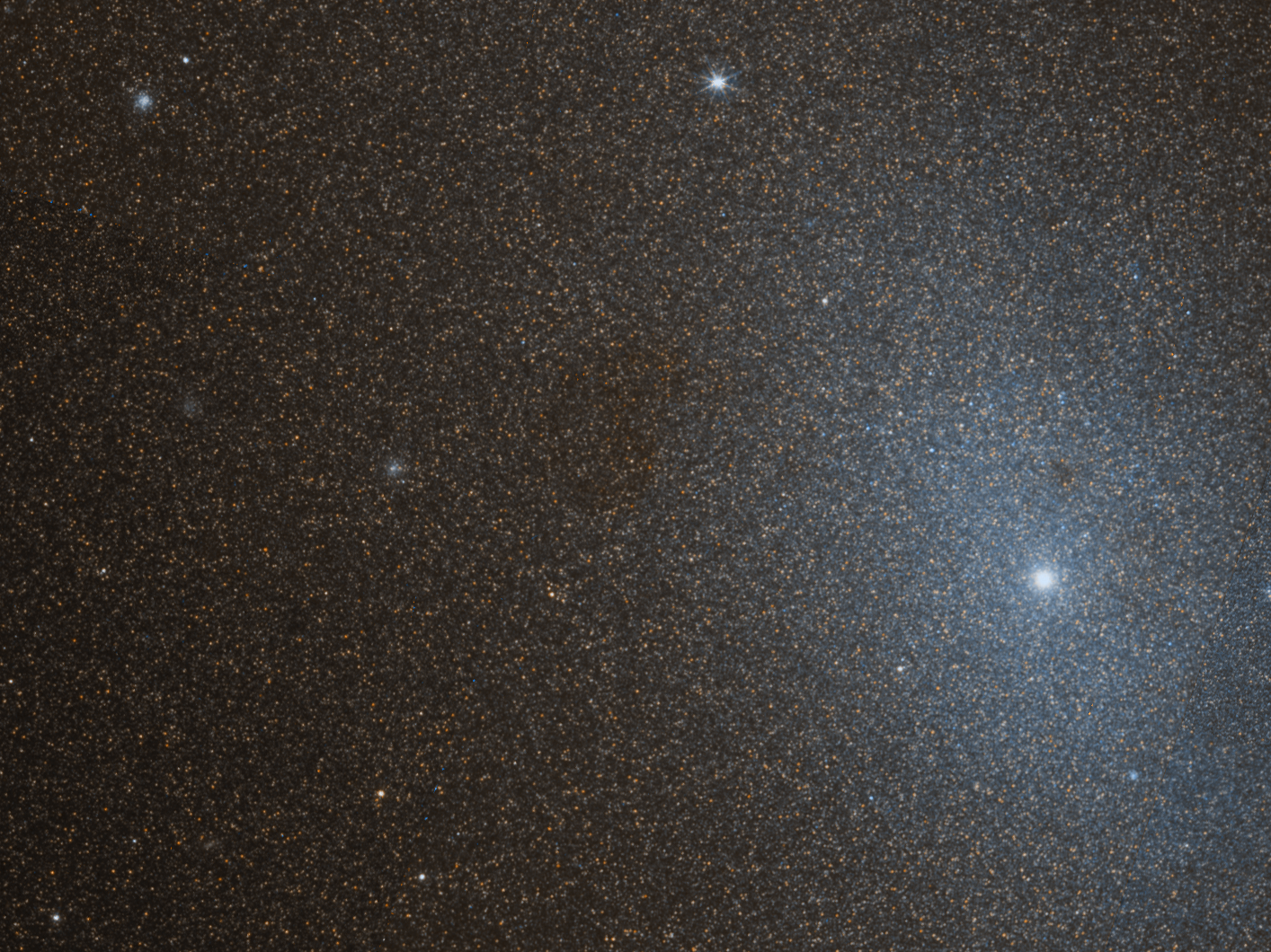 Several faint stars crowd the image, with a larger white-blue galaxy core near the right side of the image.