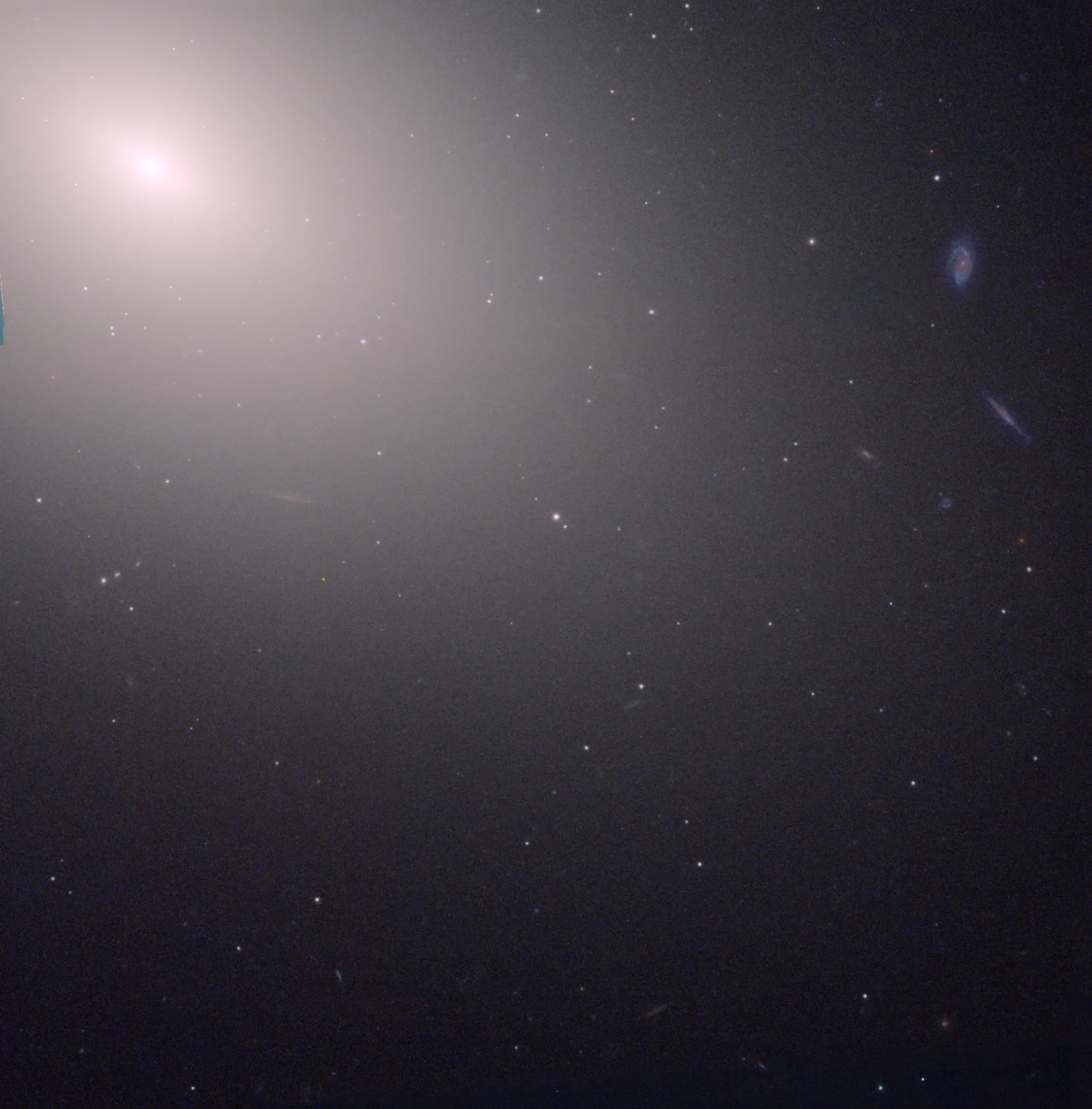 A hazy white-yellow light shines in the top left corner of the image against black space, dotted with faint, distant stars.