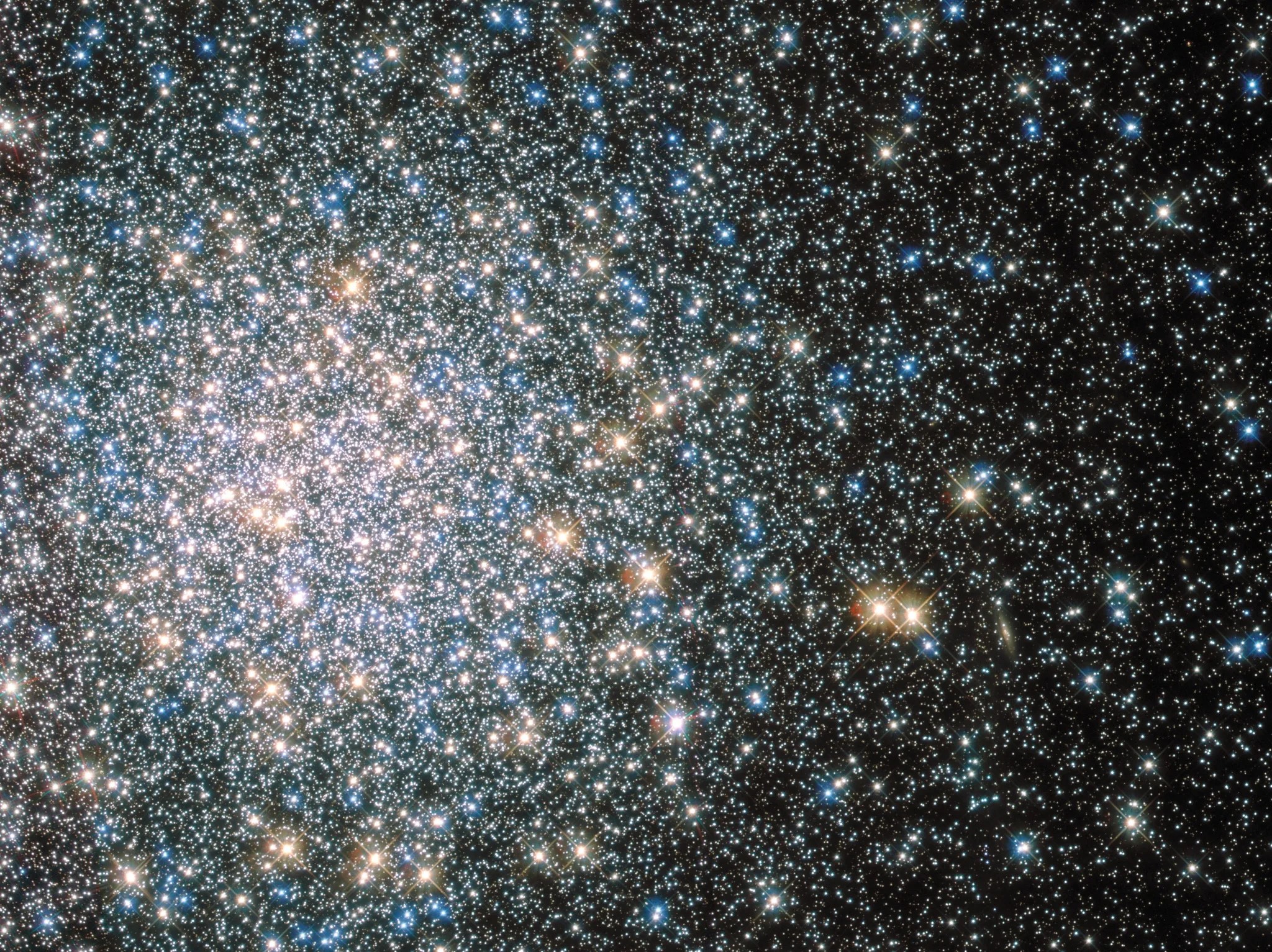 A cluster of mostly blue stars, chunks of pinkish-white and orange stars.