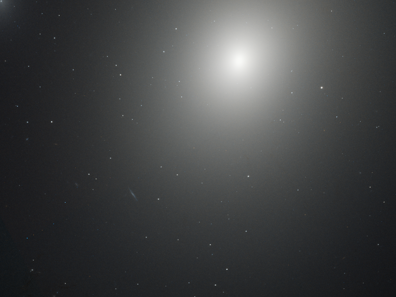 A bright, hazy point of white light shines near the top center of the image, against black space dotted with distant stars.