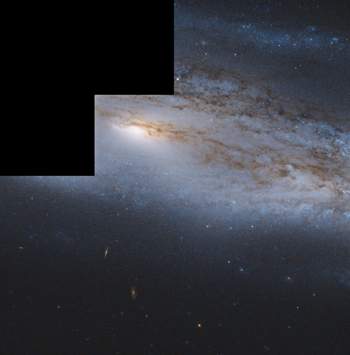 A bright yellow galaxy core shines, surrounded by spiral arms laced through with dark dust and bluish regions of star formation. A black stair step region near the upper left shows an area without Hubble data.