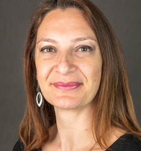 Portrait photo of a smiling woman with long brown hair and earrings.