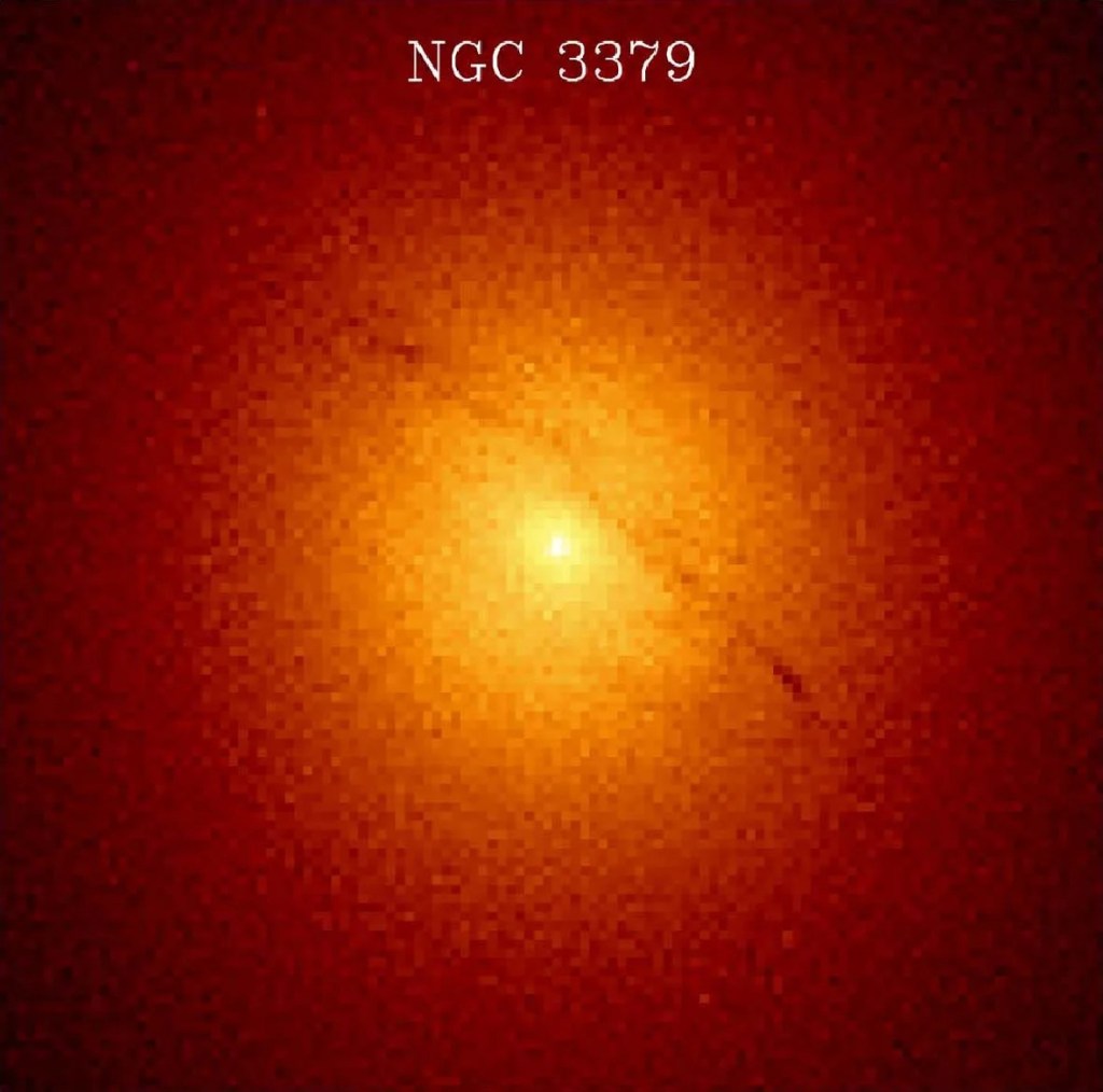 A bright, yellow-orange galaxy core shines, veering into red hues at the corners of the image.