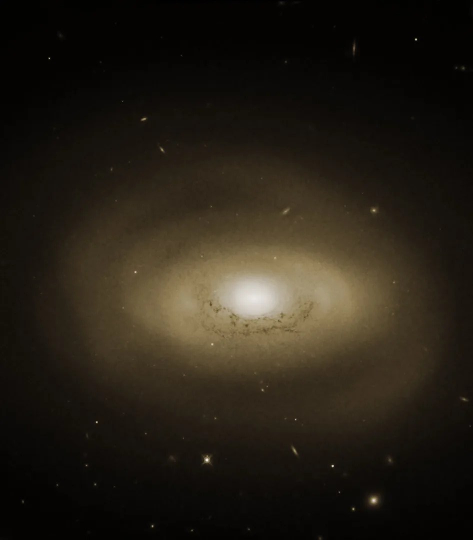 A spiral galaxy has a pale yellow glow around it, and is bright white at the center. It resembles an eye.