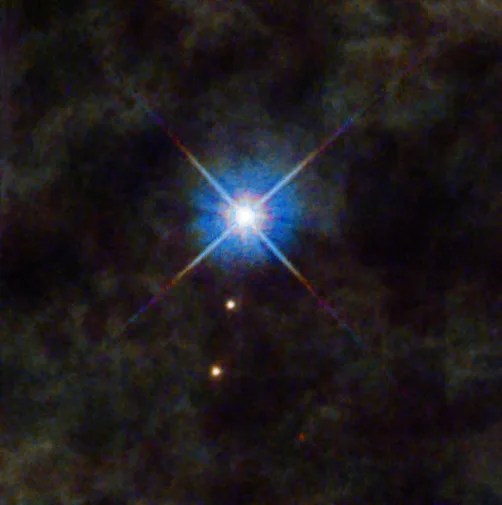 Bright blue star with diffraction spikes in front of a dusty background
