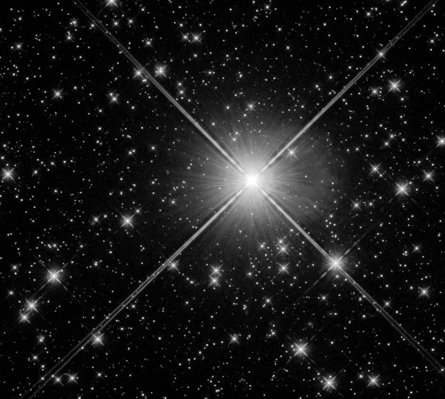 This black and white image is dominated by a single large, bright star with x-shaped beams of light emanating from it across the image. Other, smaller stars are visible around it.