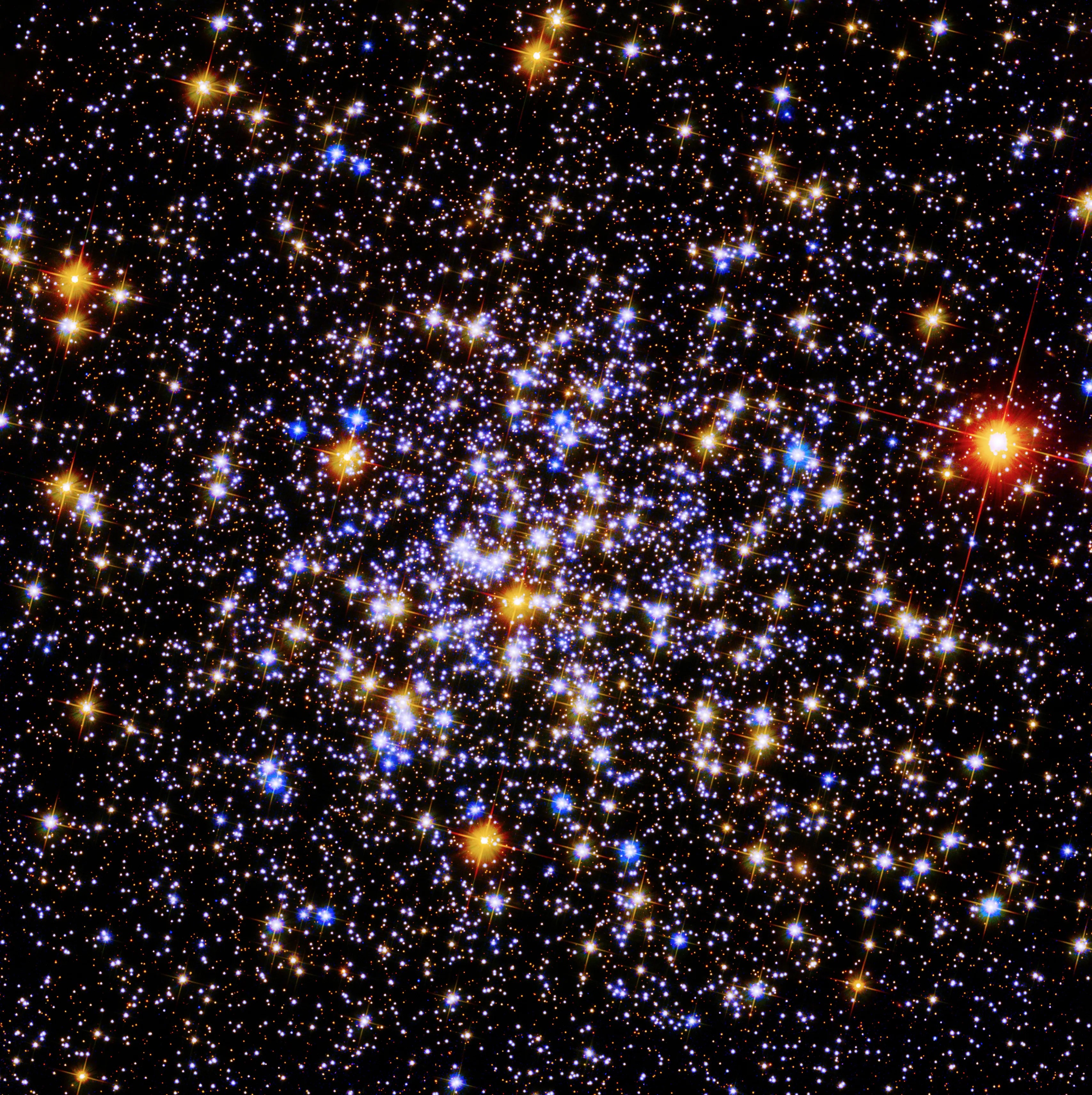 A cluster of bright blue and yellow stars against the black background of space. A single bright red star is to the far right.