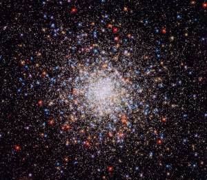 A bright, compact, spherical cluster of stars in colors of white, blue and red.