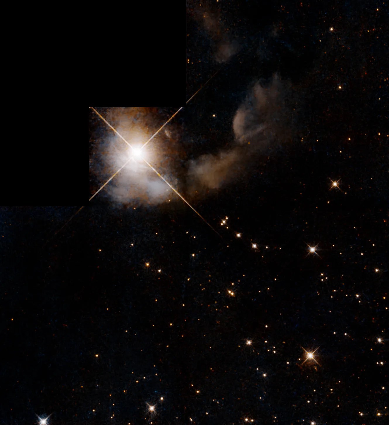 Large bright star at the top left of the image, surrounded by dark dust and gas. Stars pepper the image in the bottom right.