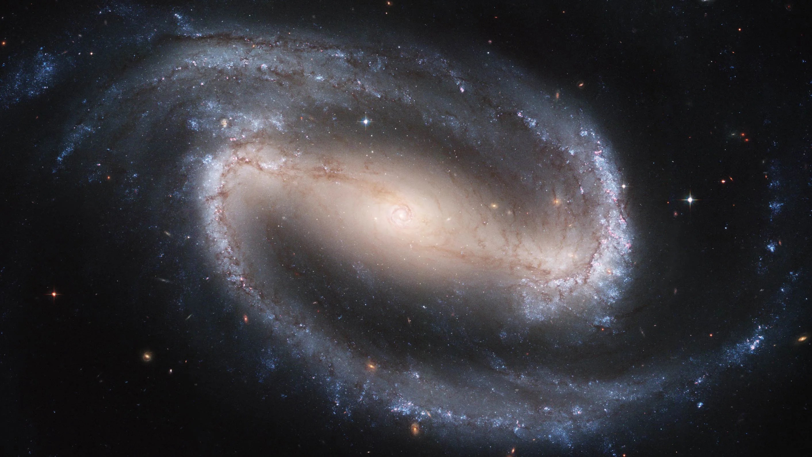 Image center holds the an oval of stars that mark the galaxy's center. Arms extend toward the upper-left and lower right of the central bulge of stars. Extending beyond the ends of each of these arms is are long curving tails that swirl above and below the galaxy.