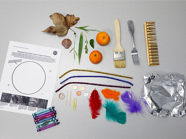 Photo of activity to color over textures, including crayons, feathers, buttons, tin foil, a comb, a fork, a paintbrush, tangerines, and a leaf