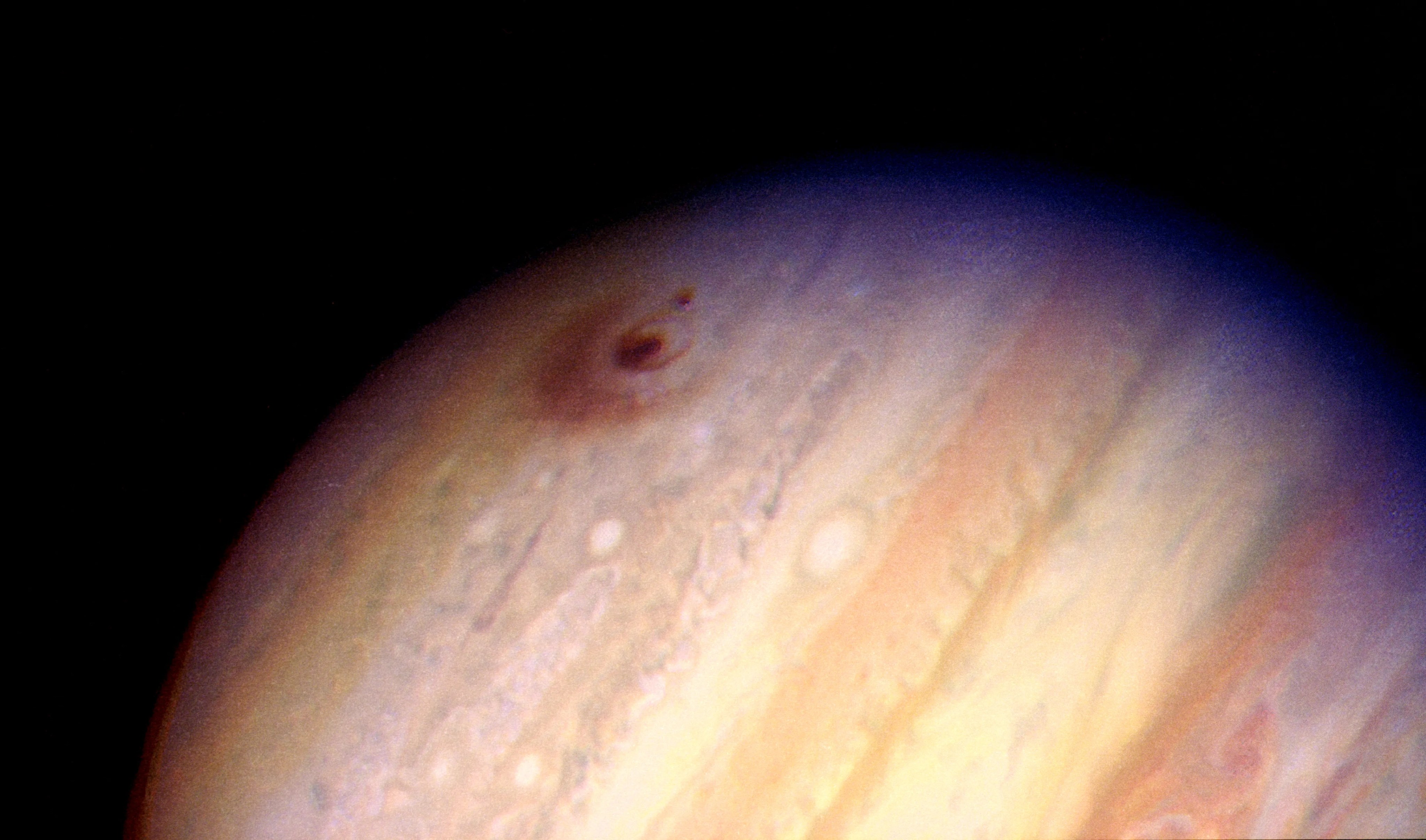 Image of jupiter with dark spot, rings in upper left