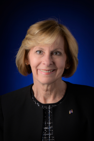 Portrait photo of a blonde haired woman with a dark blue background