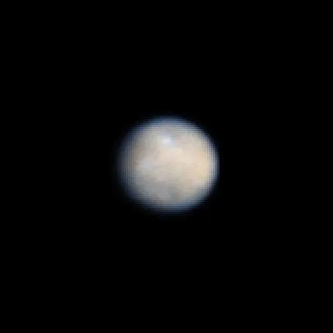 Nasa hubble space telescope color image of ceres, the largest object in the asteroid belt. It looks like a slightly blurry round ball with a pale gray and dark gray mottled appearance.