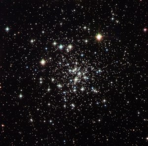 A loose concentration of a multitude of bright white stars on a black background, with the higher concentration of stars toward the center of the grouping.
