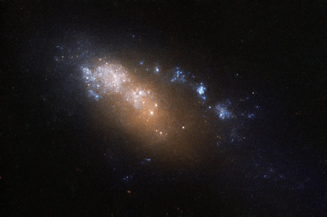 An orange-white smear of stars trailing blue-white spots