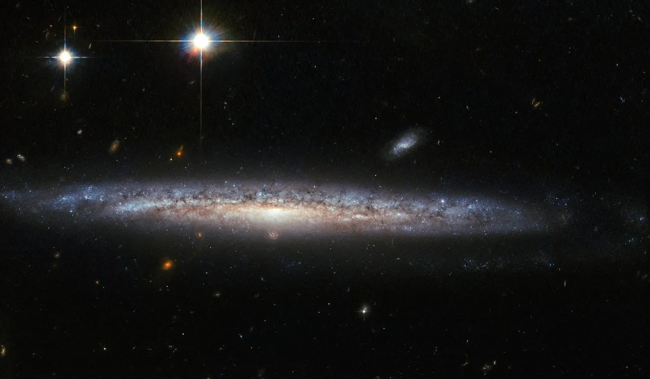Edge on galaxy with foreground stars and background spirals