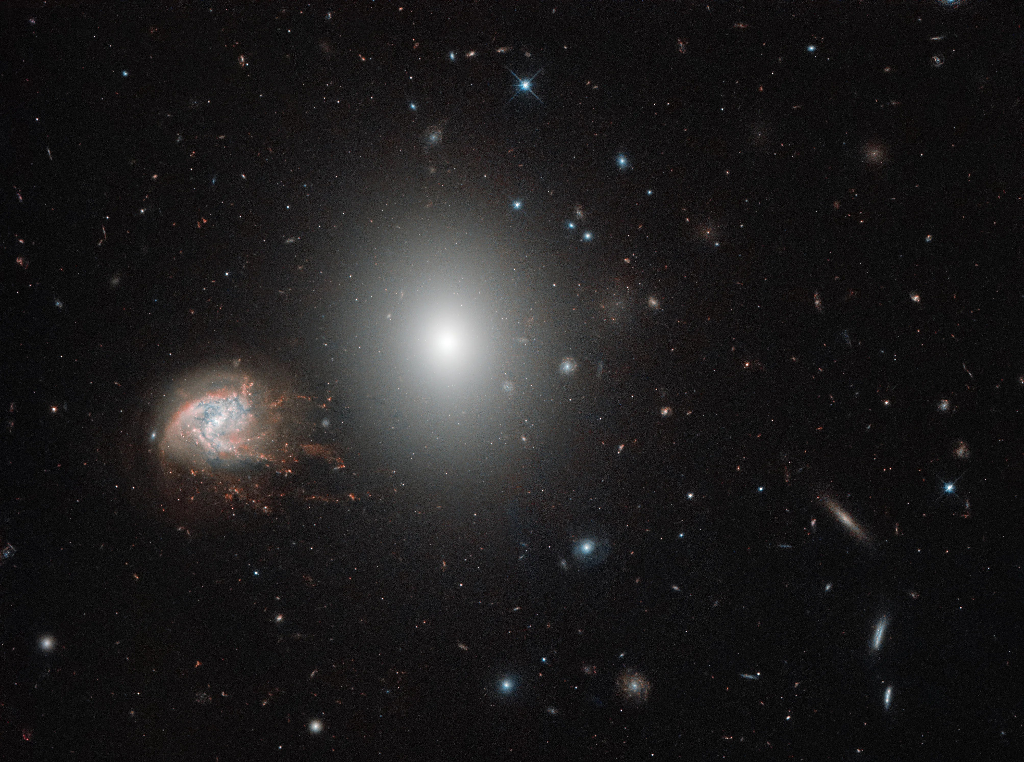 Big bright fuzzy galaxy next to small, pinkish streaked galaxy