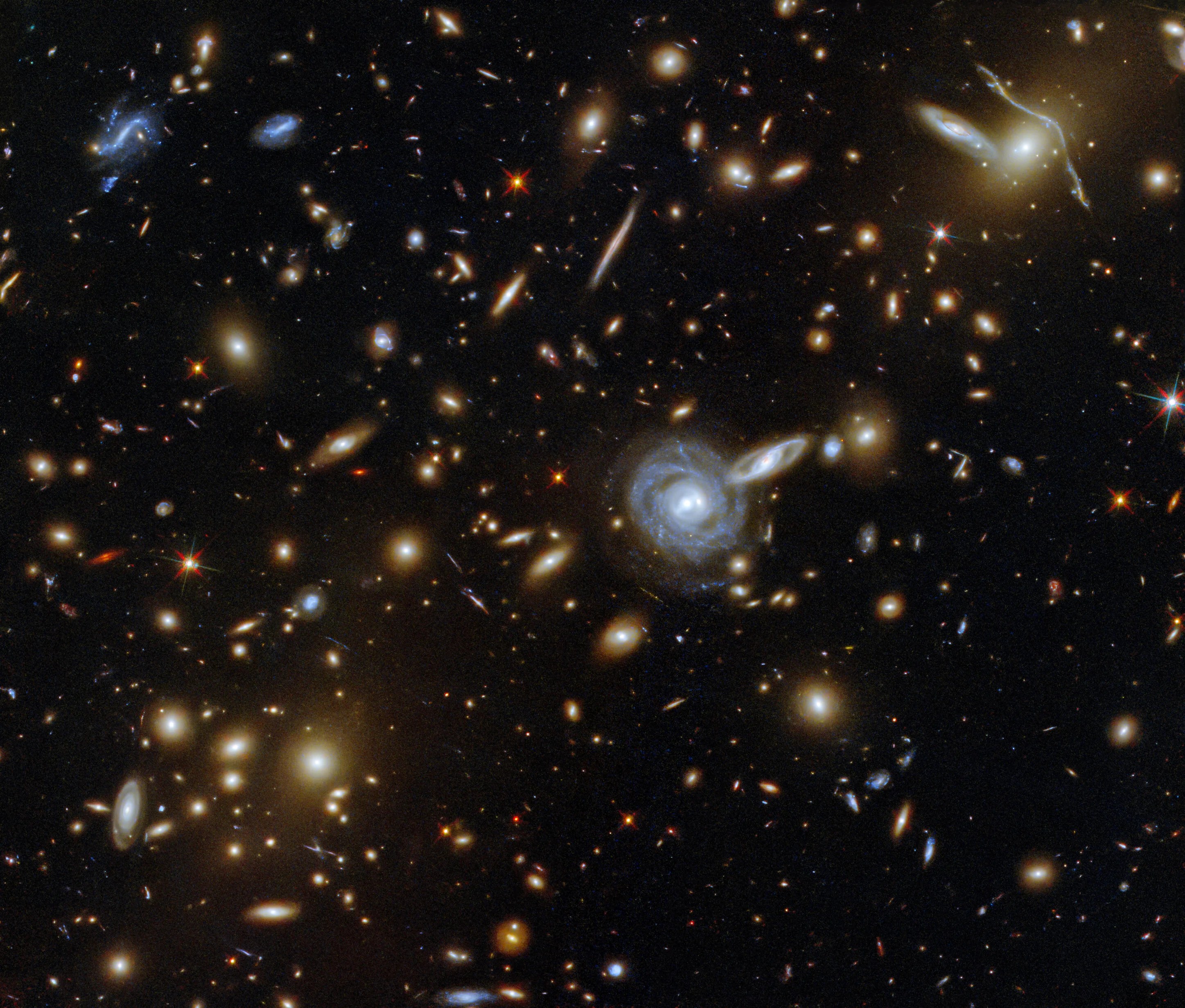 This packed image taken with the nasa/esa hubble space telescope showcases the galaxy cluster aco s 295, as well as a jostling crowd of background galaxies and foreground stars.