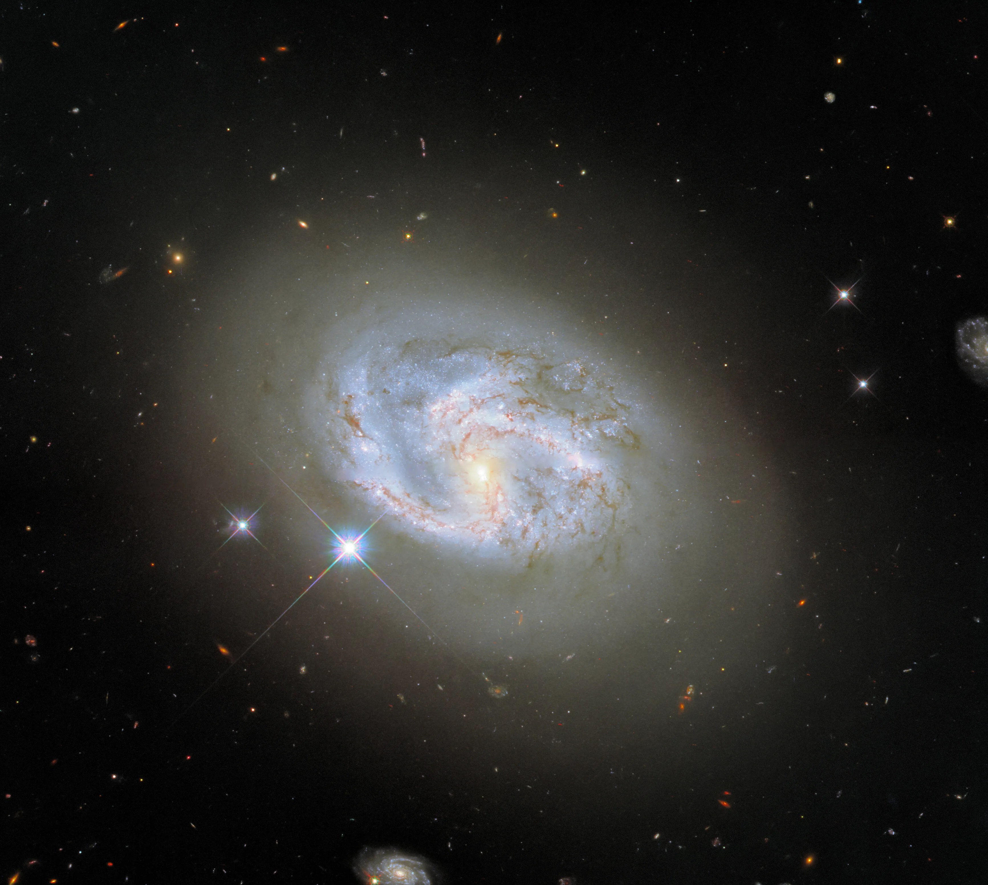 This image, taken with hubble’s wide field camera 3, features the spiral galaxy ngc 4680. two other galaxies, at the far right and bottom center of the image, flank ngc 4680.