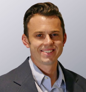 Portrait photo of a smiling young man with short brown hair and wearing a medium grey suit