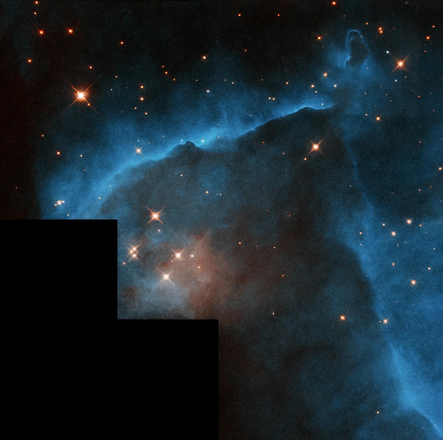 Large blue cloud of dust and gas forms a border around a grouping of yellow stars.