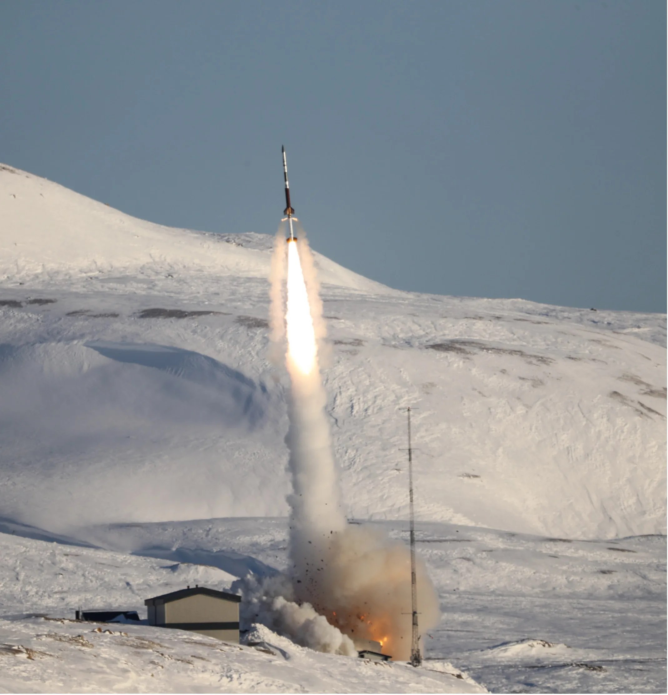 Photo of a rocket just seconds after take off with snow covered hills in the background